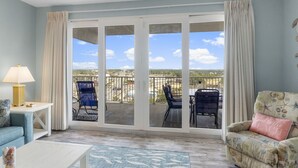 Una sala de estar con vista a un balcón, un sofá, una mesa de centro y una silla.