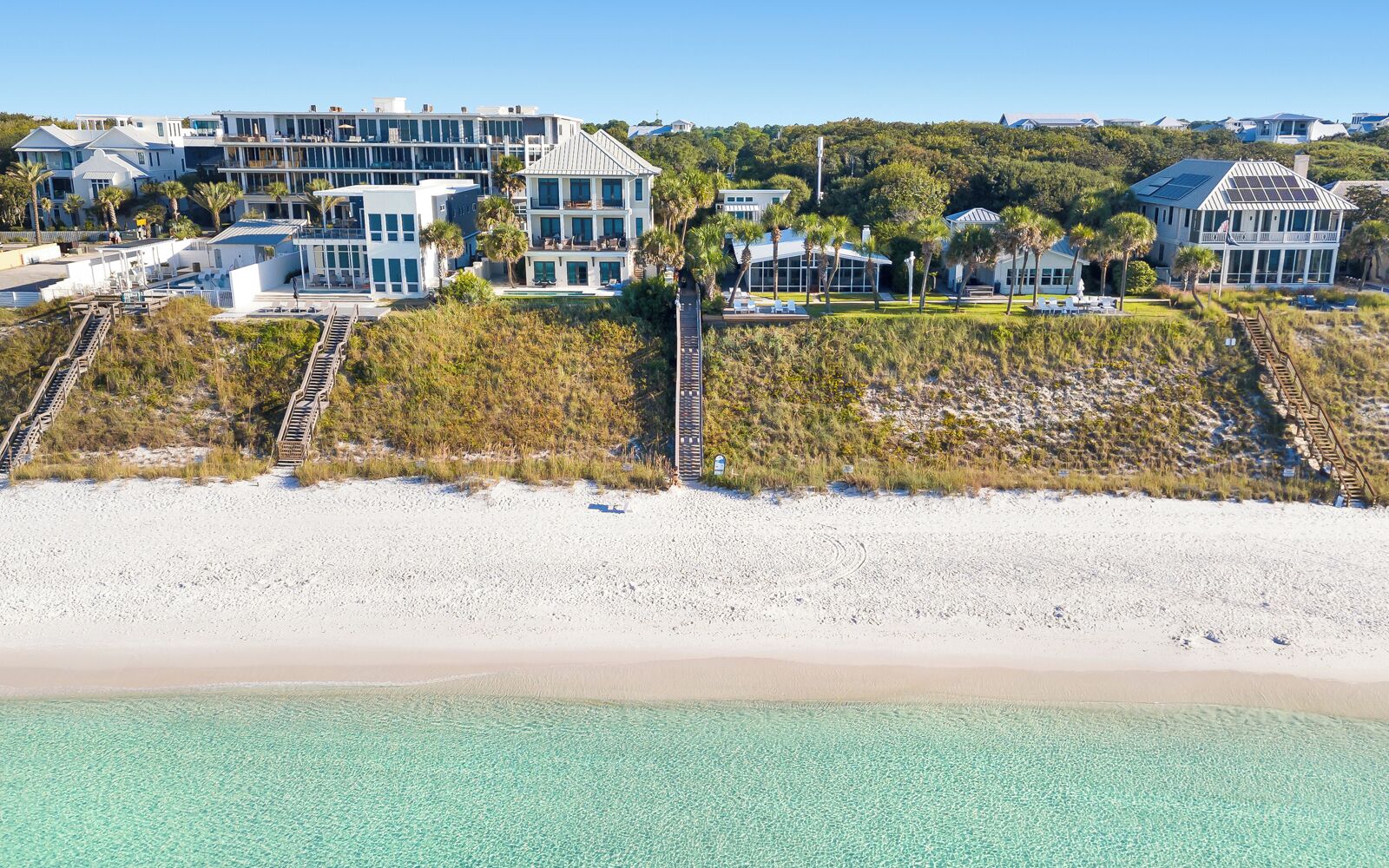 Een pand aan het strand met meerdere gebouwen, een zandstrand en helder turquoise water.