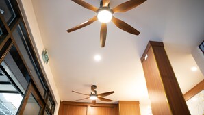 A ceiling fan with wooden blades and a light fixture in a room with wooden cabinets and a window.