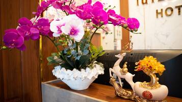 A reception desk with a white floral arrangement, a golden tree sculpture, and a white deer figurine.