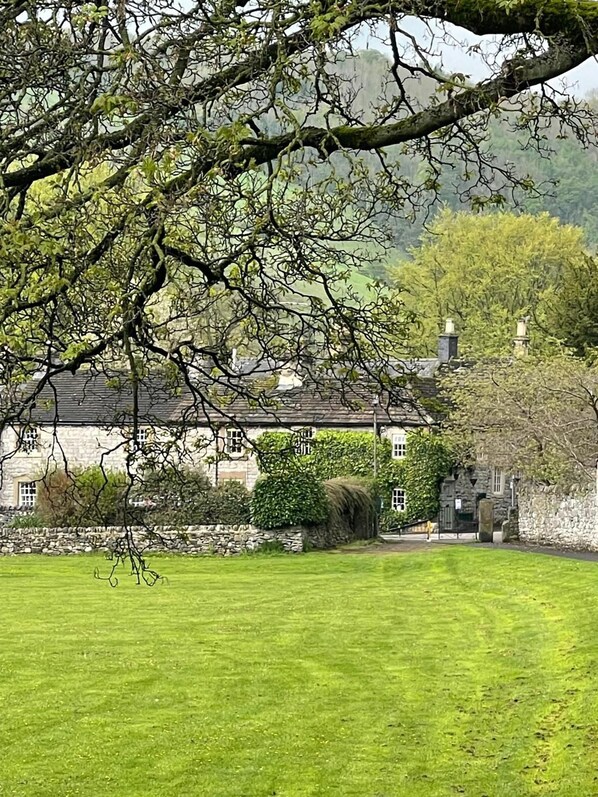 A stone building with a traditional design, surrounded by a well-maintained lawn and mature trees.