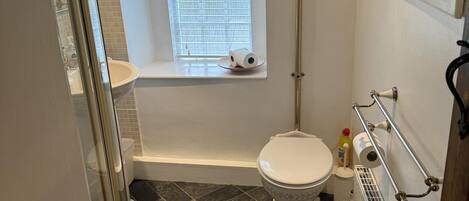 Une salle de bain avec des toilettes, une baignoire et une fenêtre.