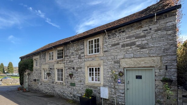 A stone building with multiple windows, a door, and potted plants. - Beautiful Cottage - 3 Bedrooms & 3 Bathrooms (Bakewell)