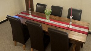 A rectangular wooden dining table with a red runner, black chairs, and two candle holders with red candles. - Beautiful Cottage - 3 Bedrooms & 3 Bathrooms (Bakewell)