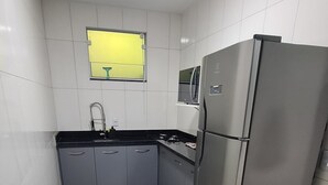 A modern kitchen with grey cabinets, a stainless steel refrigerator, a microwave, and a gas stove.