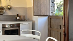 Une cuisine avec des meubles blancs, une cuisinière et une table à manger avec des chaises.