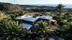 Une villa dotée d’une terrasse sur le toit offrant une vue sur un paysage côtier.