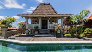 A traditional wooden pavilion with a tiled roof, a pool, and lush greenery. - Billys Ayodya Villa (Perean Tengah)