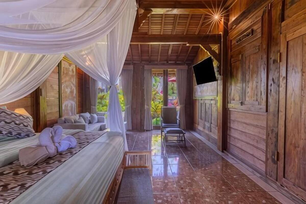 A room with a bed, a chair, a TV, and a wooden wall.