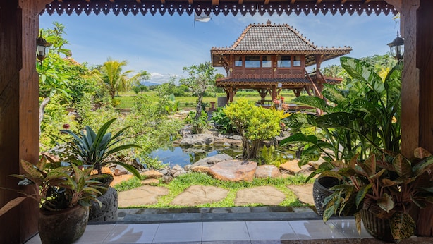A traditional wooden pavilion with a tiled roof, surrounded by lush greenery and a small pond. - Billys Ayodya Villa (Perean Tengah)