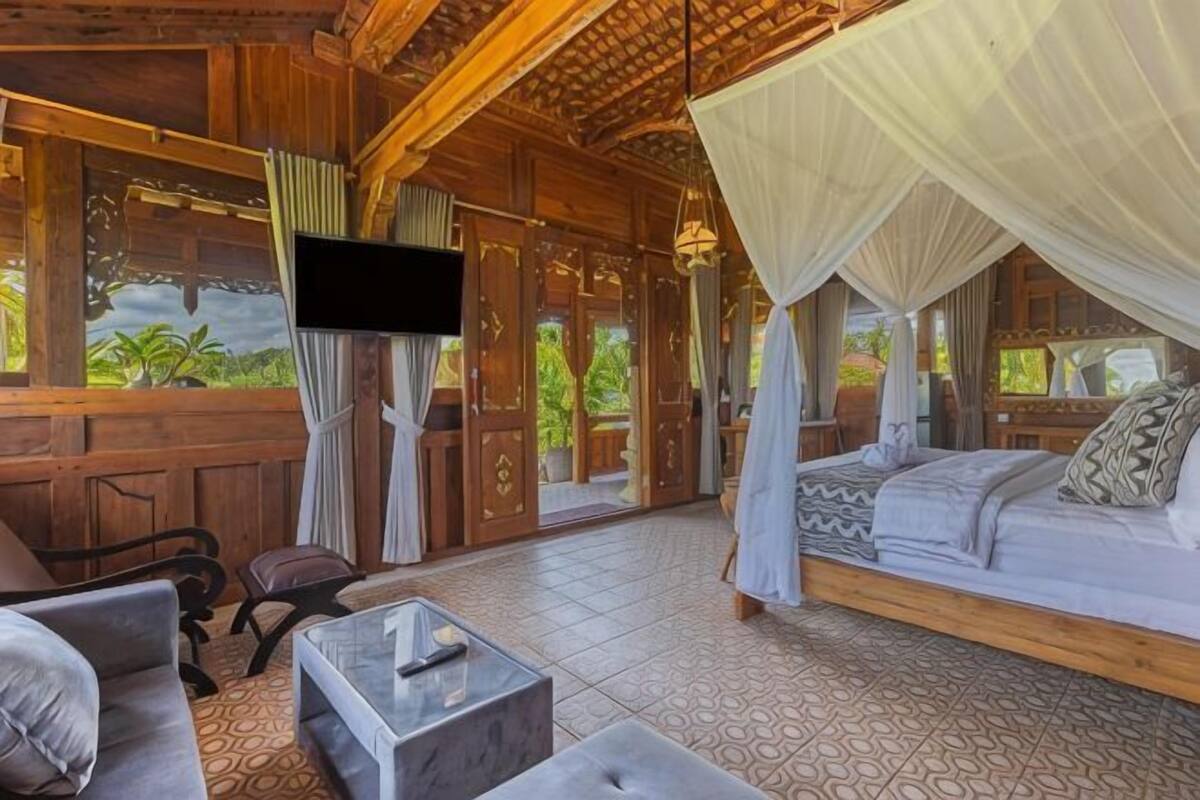 A wooden room with a bed, a sofa, a TV, and a TV stand.