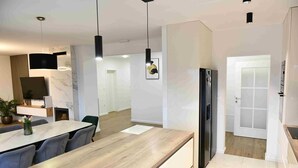 Una cocina moderna con encimera de madera, refrigerador integrado e iluminación colgante.