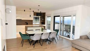 Una cocina moderna con armarios de madera, una isla central y una zona de comedor con mesa y sillas.
