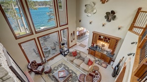 A spacious living area with a view of the sea, a dining area, and a kitchen with wooden cabinets. - Luxury Lakefront! Hot Tub & Arcades! Sleep 24! (Wautoma)