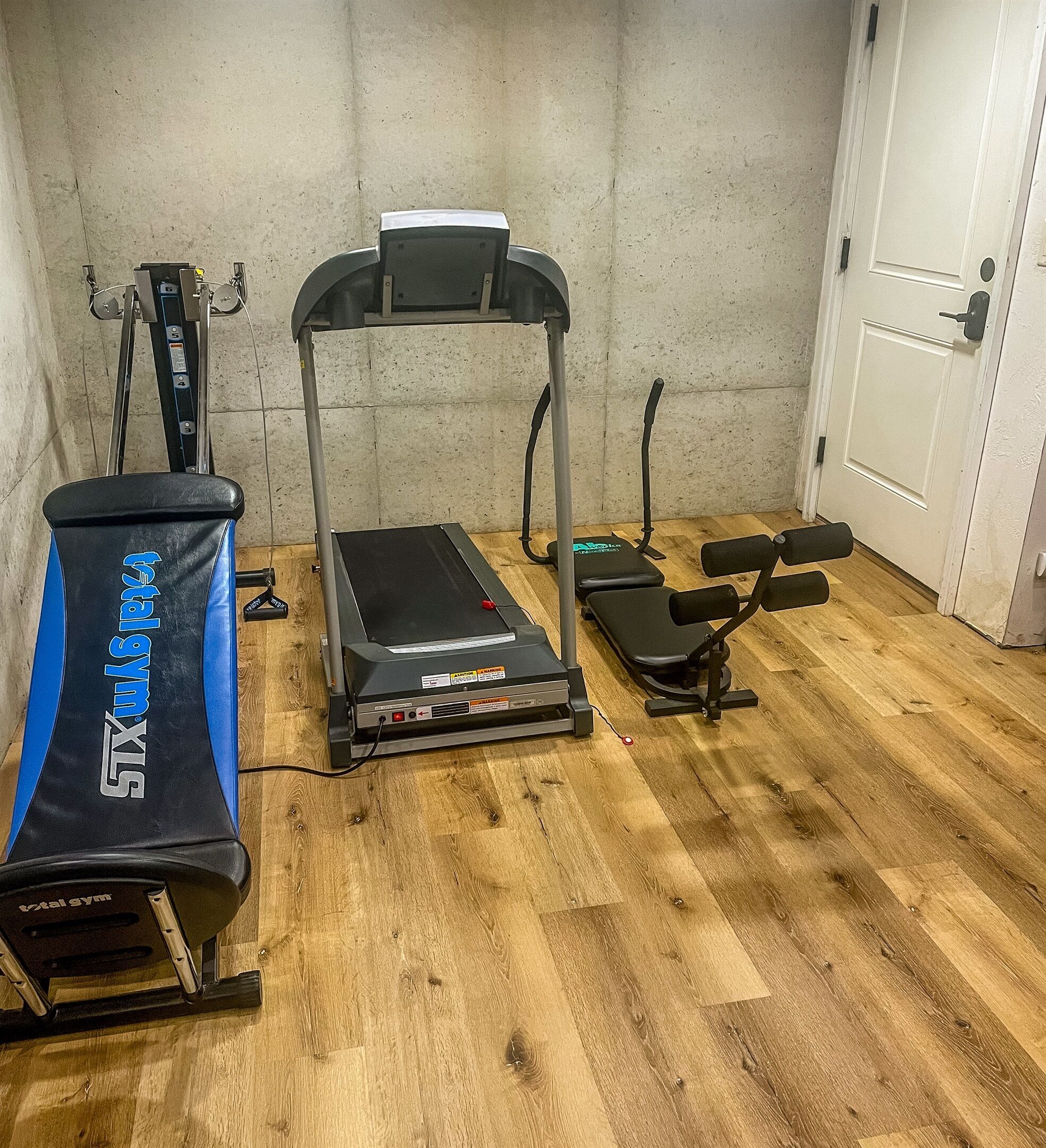 A home gym with a treadmill, dumbbells, and a stationary bike.
