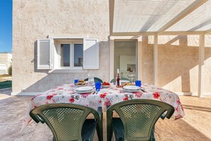 An outdoor dining area with a table set for two, covered with a floral tablecloth, and two green chairs. - 3714 Villa Alba e Tramonto - Alba by Barbarhouse (Porto Cesareo)