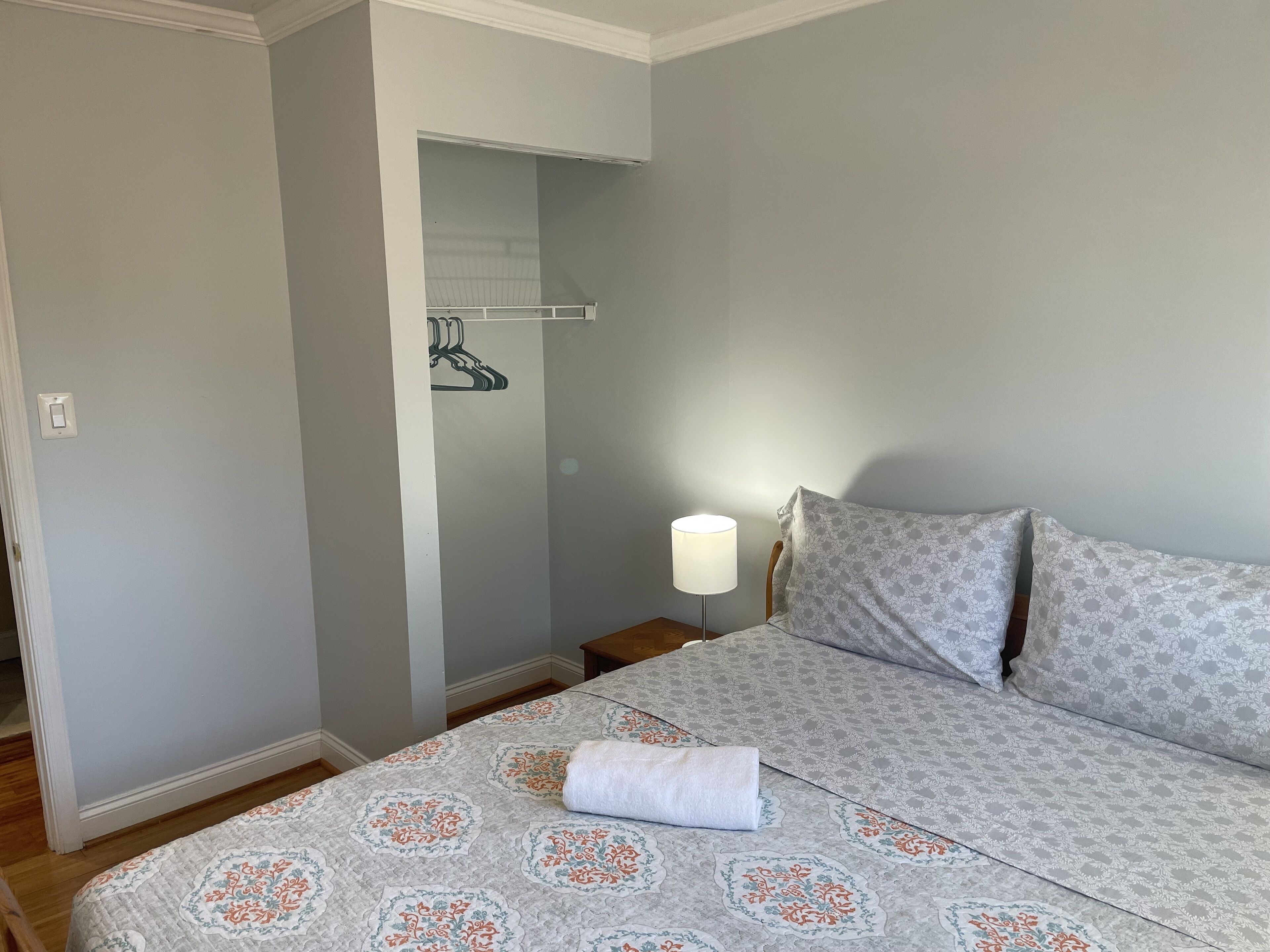 Une chambre à coucher avec un lit, une table de chevet, une lampe et une armoire.