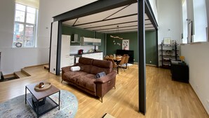 A spacious living room with a brown leather sofa, a coffee table, and a dining area with a wooden table and chairs. - Cityloft Gold - im Zentrum. Inkl. Parken, Netflix (Leipzig)