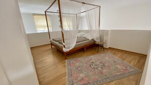 A bedroom with a four-poster canopy bed, a small round table, and a patterned rug. - Cityloft Gold - im Zentrum. Inkl. Parken, Netflix (Leipzig)
