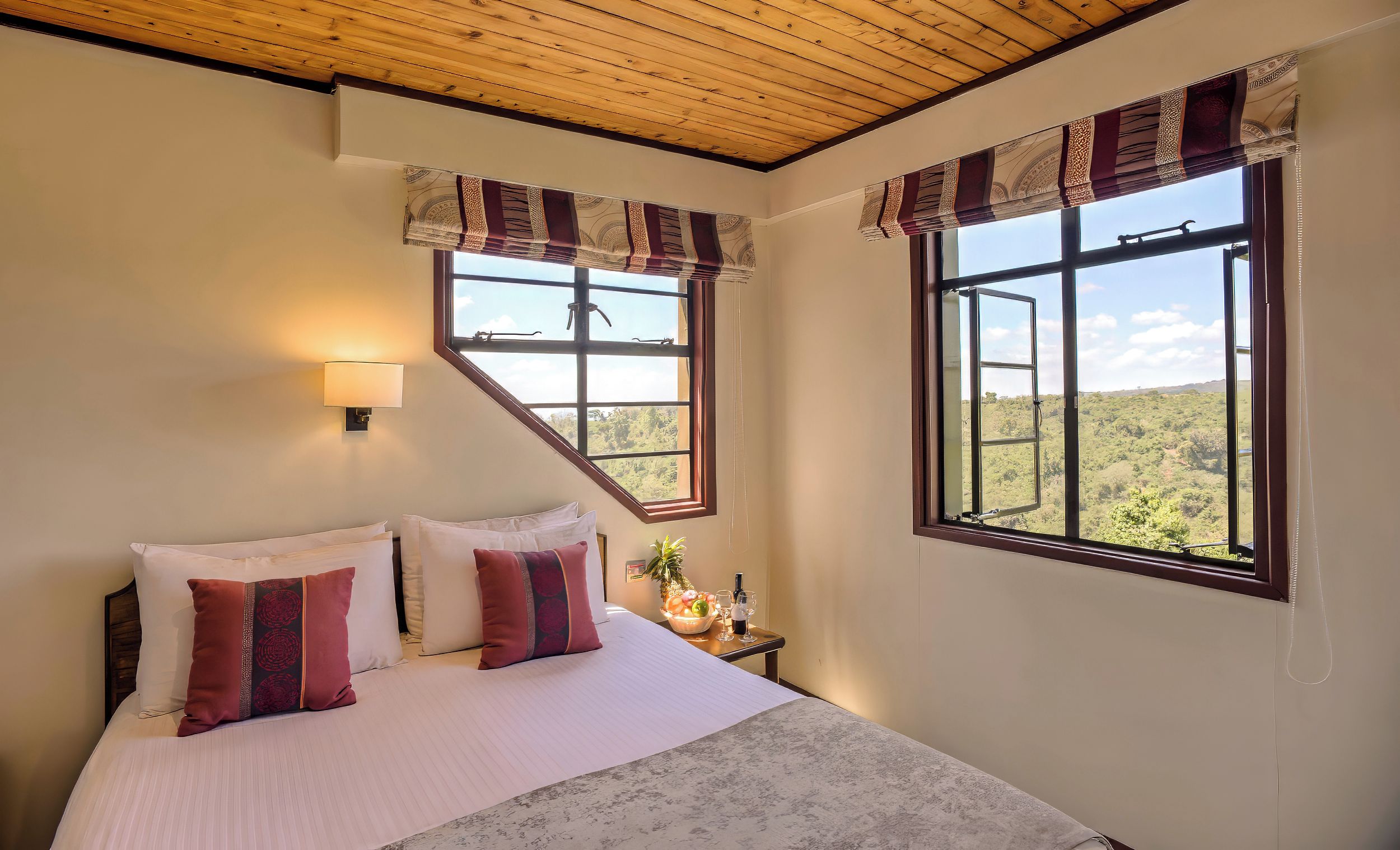 A bedroom with a bed, two windows, a nightstand, and a lamp.