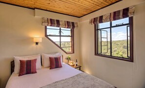 A bedroom with a bed, two windows, a nightstand, and a lamp. - The Ark Lodge (Aberdare National Park)