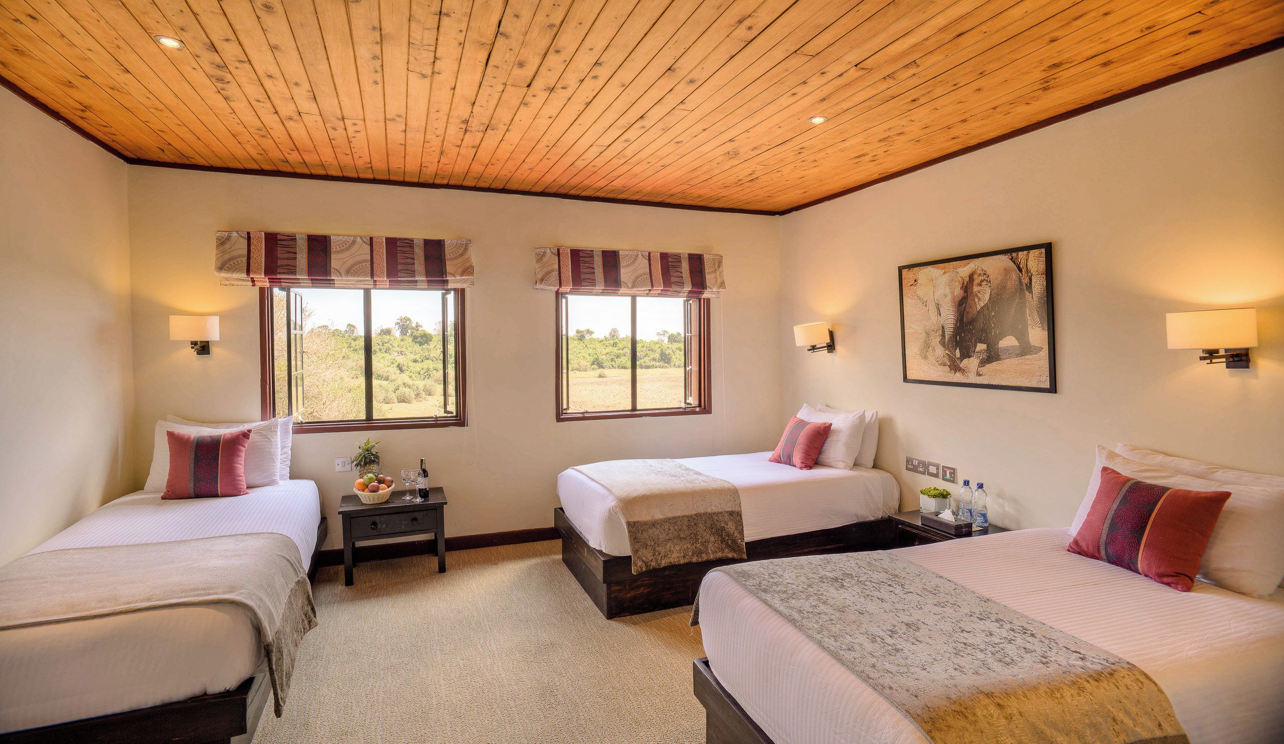 A hotel room with two beds, a large window, and a painting on the wall.
