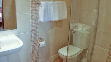 Un baño con lavamanos, inodoro y cabina de ducha de vidrio.