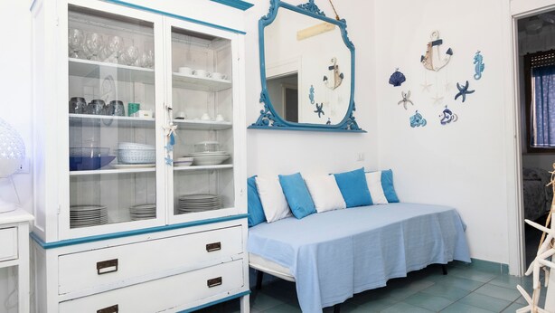 A bedroom with a bed, a white cabinet with glass doors, and a mirror with a blue frame.