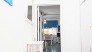 A hallway leading to a dining area with a table and chairs, a ceiling fan, and a window with curtains.