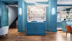 A modern bar area with teal cabinetry, a wooden floor, and a bar counter with a laptop and a white towel. - Glimpse Hotel (Florence)