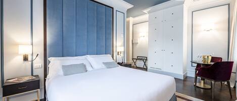 A modern hotel room with a large bed, a desk, and a seating area with a table and chairs.