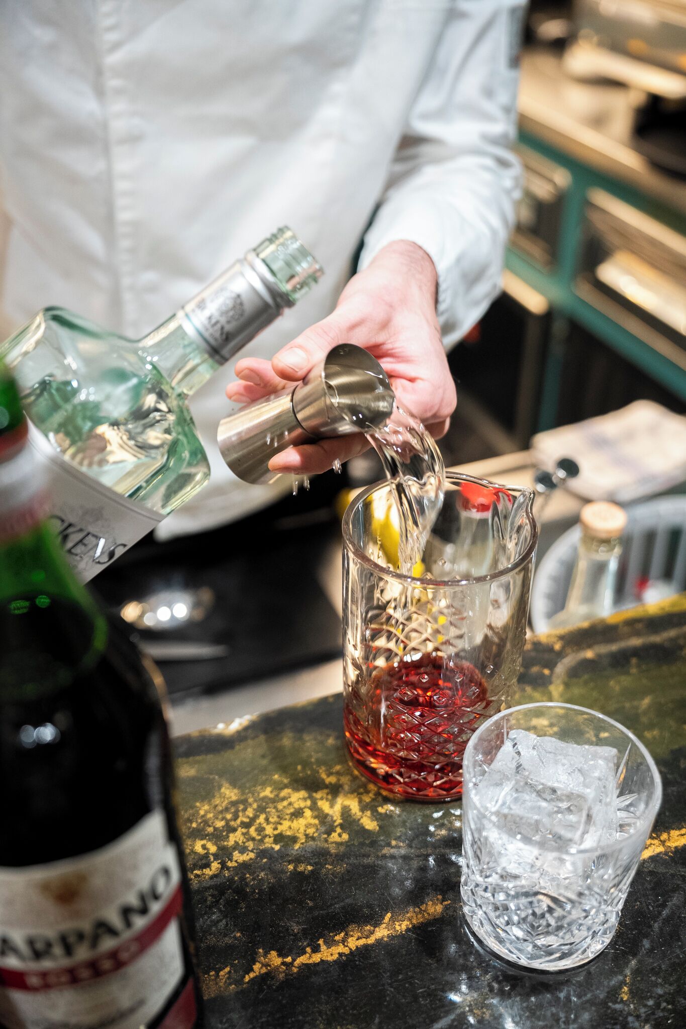 A person pouring a drink from a bottle into a glass.