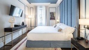 A modern hotel room with a large bed, a flat-screen TV, a desk with a lamp, and a view of the outdoors. - Glimpse Hotel (Florence)
