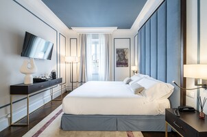 Camera d'albergo moderna con un letto grande, una televisione a schermo piatto, una scrivania con lampada e vista sull'esterno.