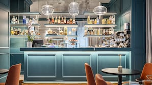 A bar area with shelves of bottles, a counter, and seating with tables and chairs. - Glimpse Hotel (Florence)