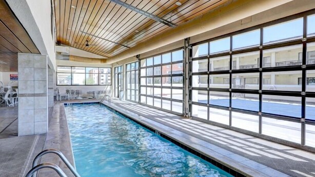 Una piscina interior con ventanas transparentes y techo de madera.