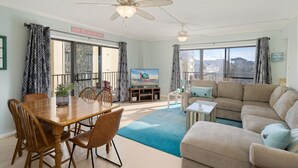 Amplia sala de estar con comedor, televisor grande y vista panorámica de la ciudad.