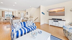 A spacious living room with a striped sofa, a coffee table, and a TV.