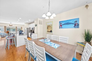 Un comedor con una mesa de madera, sillas blancas y un mantel individual azul.