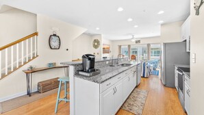 A modern kitchen with a large island, white cabinetry, and a built-in oven.
