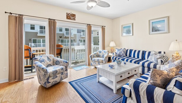 A living room with a sofa set, armchairs, a coffee table, and a ceiling fan.