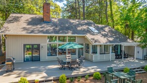 A house with a large deck, outdoor seating, and a covered patio area.