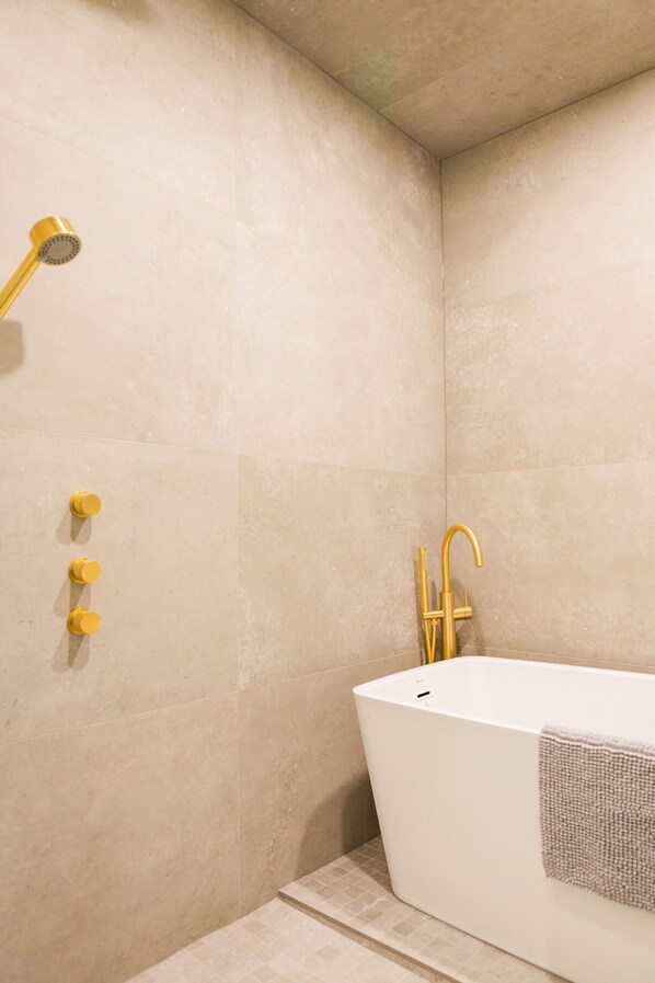Une salle de bain moderne avec une baignoire sur pieds, une pomme de douche et un porte-serviettes.