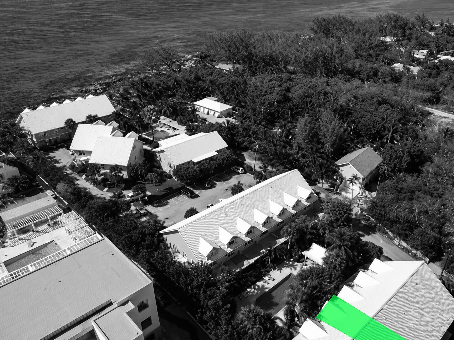 Vista aerea di una zona residenziale con diverse case, una piscina e una vasta area verde.