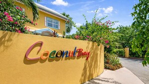 A sign with 'Coconut Bay' written in colorful letters on a yellow wall.