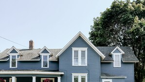 A two-story house with a front porch, a chimney, and a small front yard.