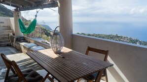 A wooden table and chairs on a balcony with a view of the sea and a distant town.