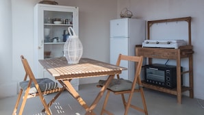 A compact kitchen with a wooden table and chairs, a white refrigerator, a microwave, and a small cabinet.