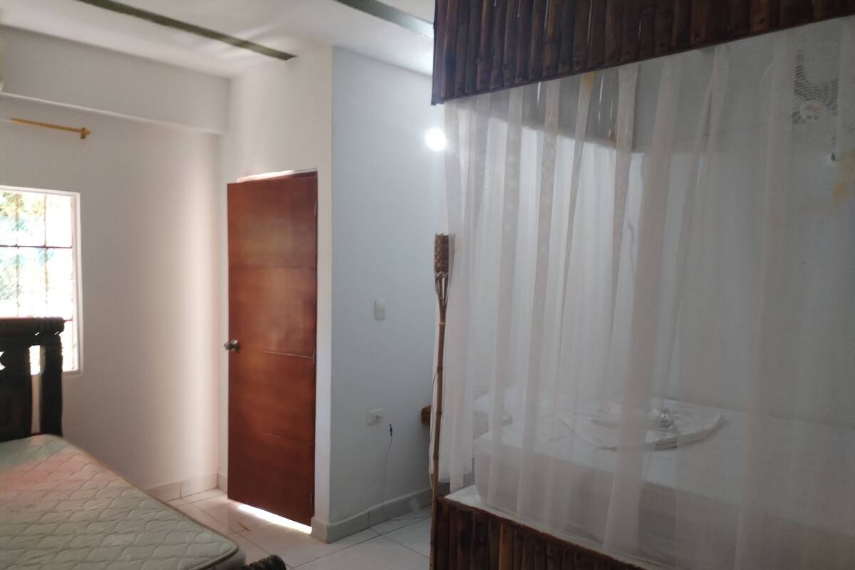 A room with a bed, a wooden door, and a window with blinds.