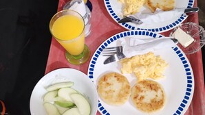 A tray with breakfast items including scrambled eggs, potato pancakes, and sliced apples, along with glasses of orange juice. - Hostal Principio Tayrona (Santa Marta)